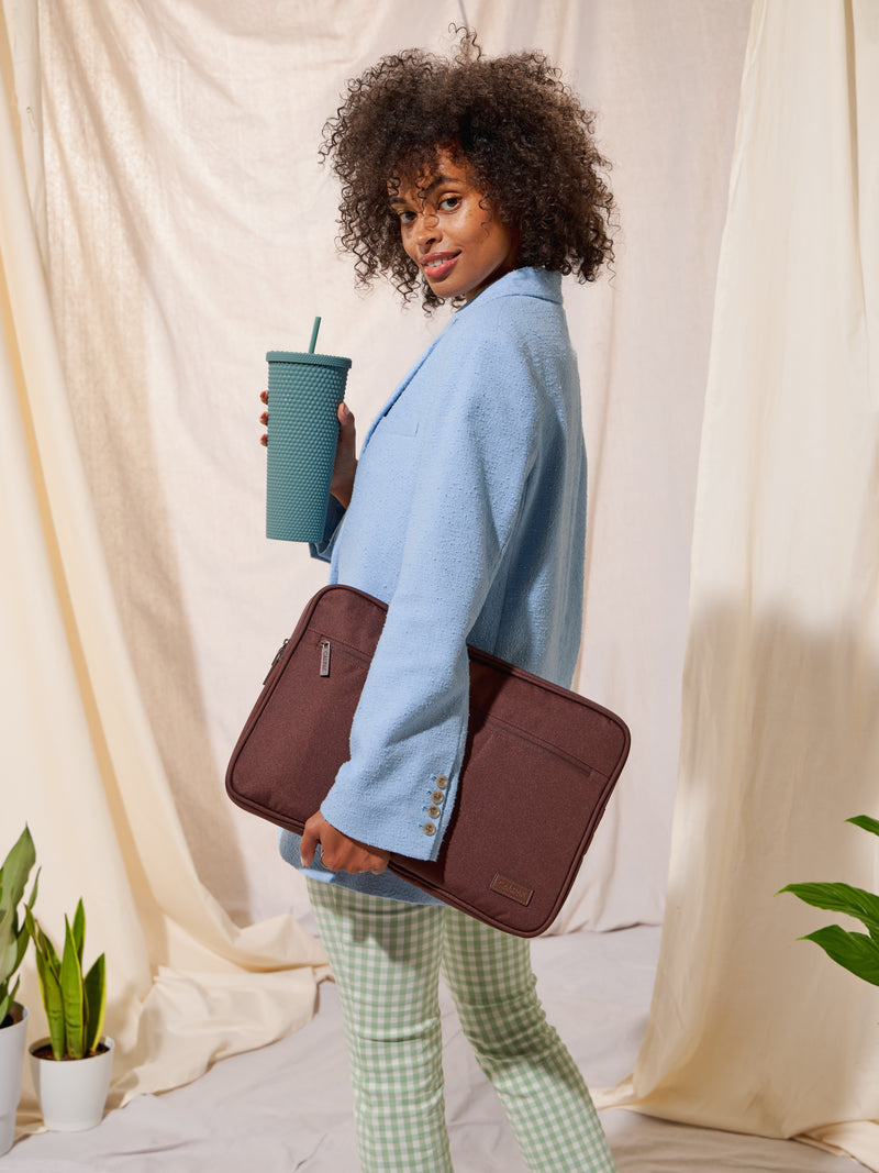 Model holding CALPAK 15-17 Inch Padded Laptop Sleeve in walnut brown