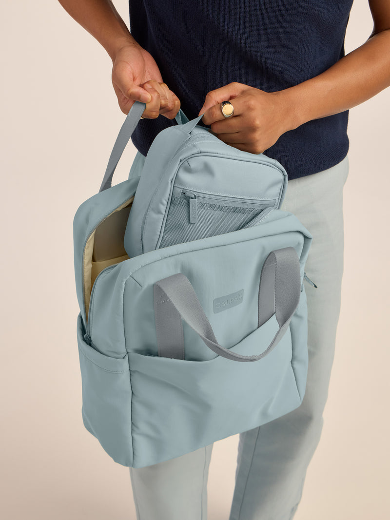 Model putting in the CALPAK Everything Cube in blue Bluebell in CALPAK Connect Backpack