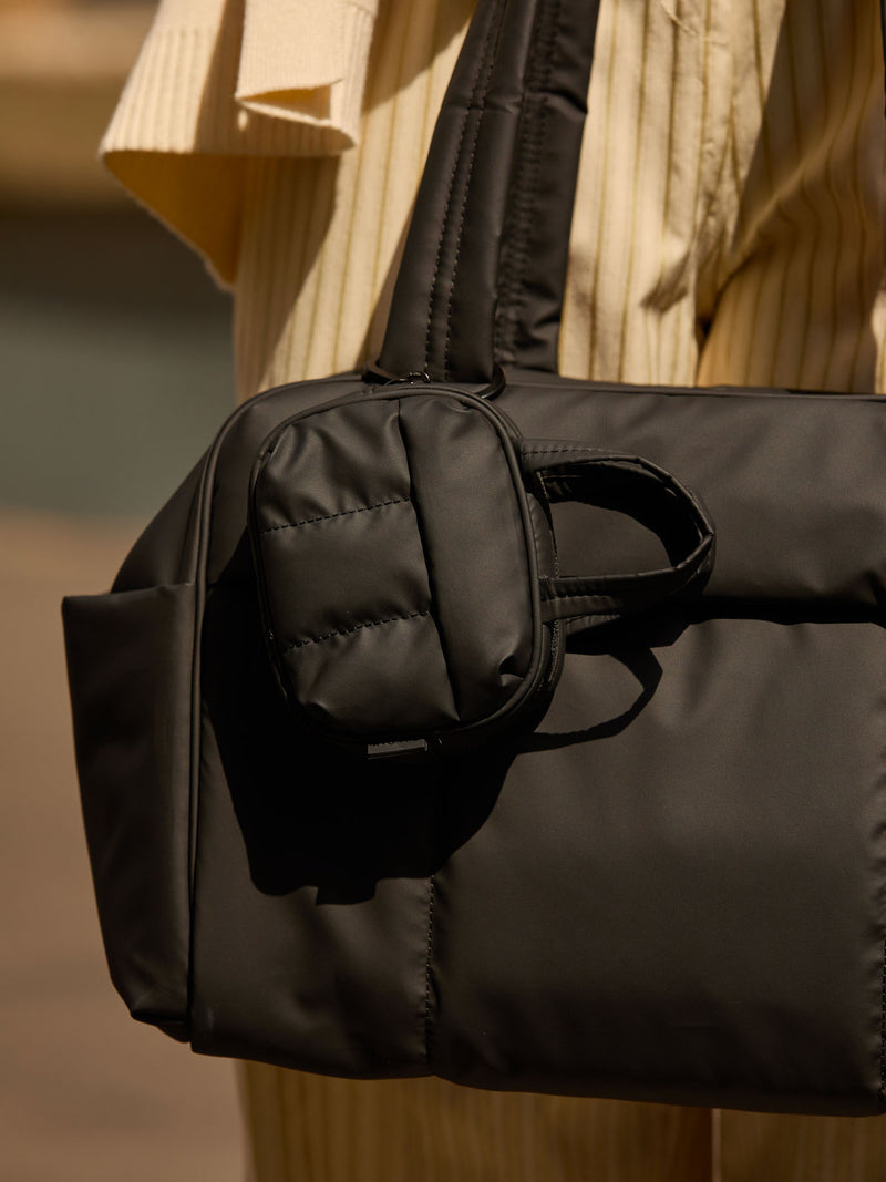 CALPAK Luka Duffel Key Pouch in pink Matte Black clipped onto the Luka Duffel in pink Matte Black being held by a model