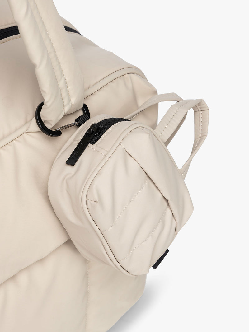 CALPAK Luka Duffel Key Pouch in white Oatmeal clipped onto the Luka Duffel in white Oatmeal