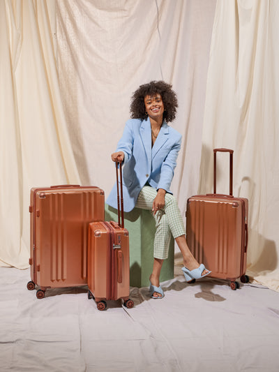 Model with all 3 pieces of the Ambeur luggage set in copper