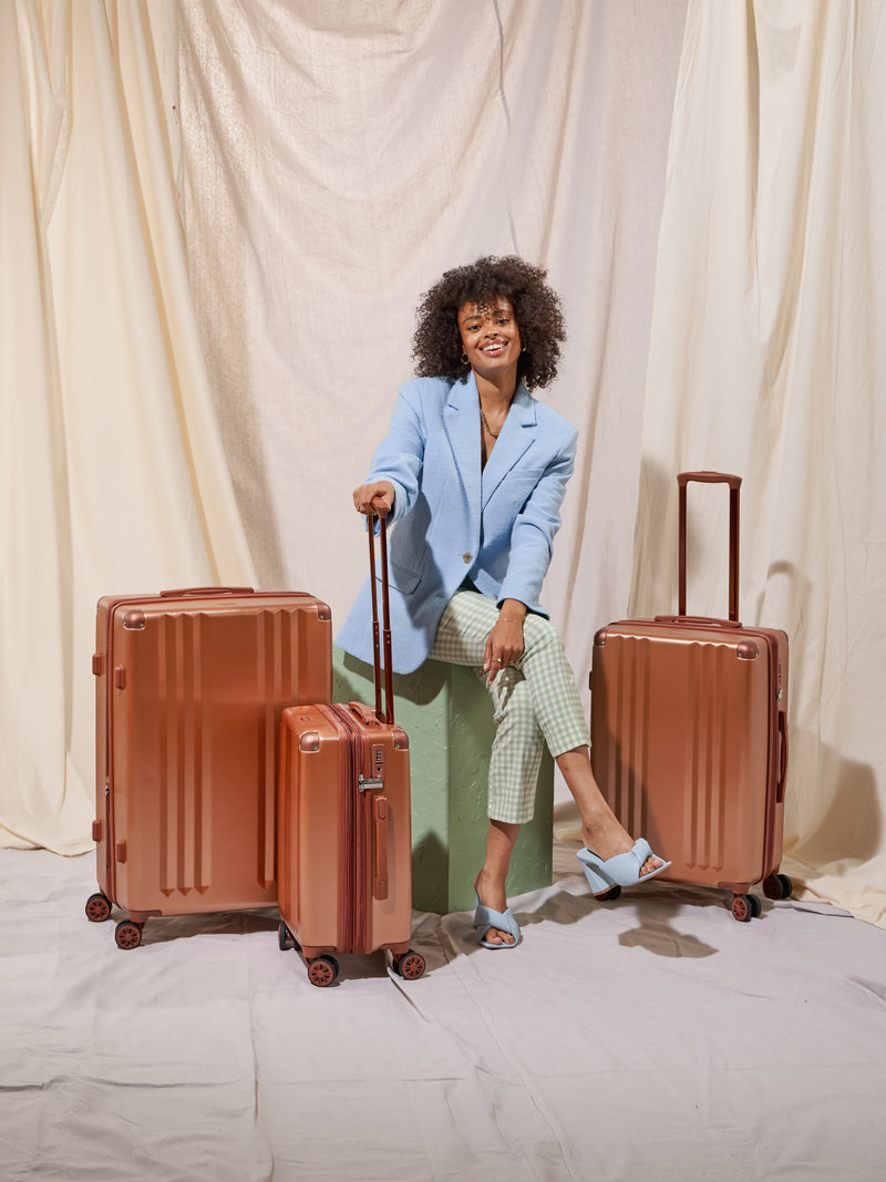 Model with all 3 pieces of the Ambeur luggage set in copper