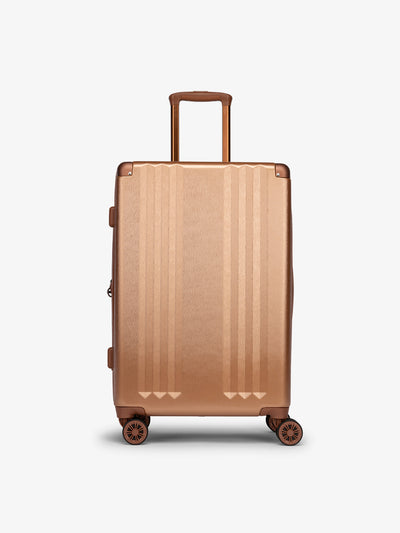 Studio product shot of front-facing CALPAK Ambeur medium 26-inch lightweight hardshell luggage with 360 spinner wheels in copper; LAM1024-COPPER view 1