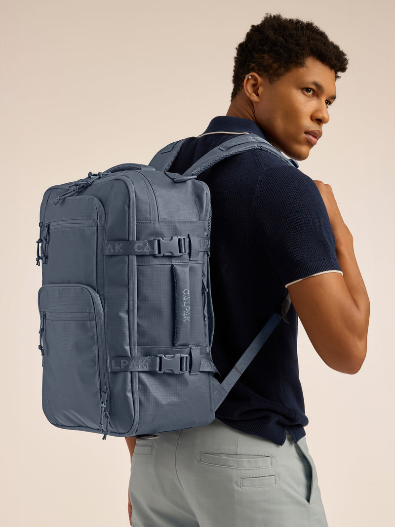 Model wearing the CALPAK Terra 26L Laptop Backpack Duffel in blue Matte Indigo