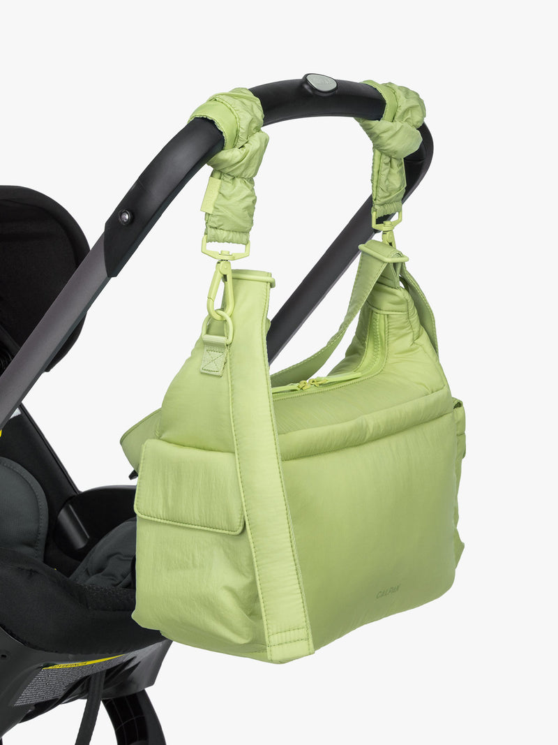 CALPAK Crossbody Diaper Bag in light green Lime strapped on stroller with Stroller Straps