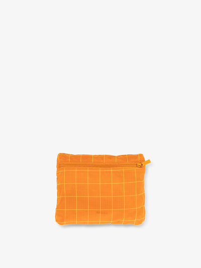 CALPAK Compakt foldable duffle bag for travel in orange grid print