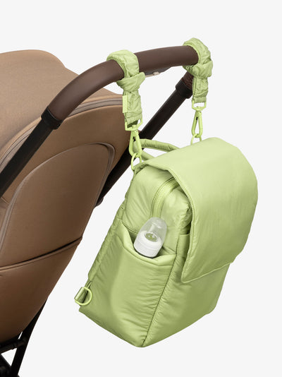 CALPAK Convertible Mini Diaper Backpack attached to stroller by CALPAK Stroller Straps in lime green; BPC2401-LIME, BBPC2401-LIME