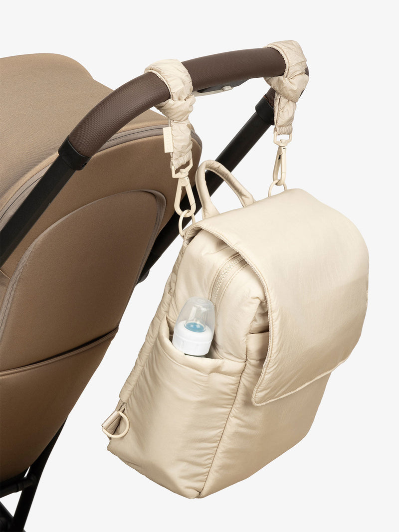 CALPAK Convertible Mini Diaper Backpack attached to stroller by CALPAK Stroller Straps in beige oatmeal