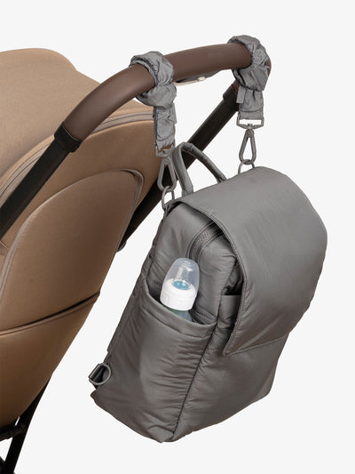 CALPAK Convertible Mini Diaper Backpack attached to stroller by CALPAK Stroller Straps in slate gray; BPC2401-SLATE, BBPC2401-SLATE