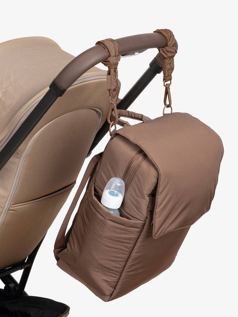 CALPAK Diaper Backpack in brown Hazelnut with brown Hazelnut Stroller Straps attached to a brown stroller