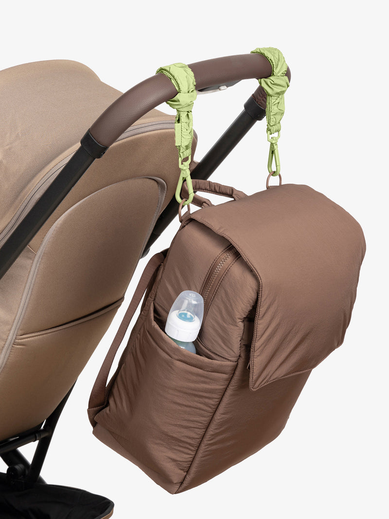 CALPAK Diaper Backpack in brown Hazelnut with light green Lime Stroller Straps attached to a brown stroller