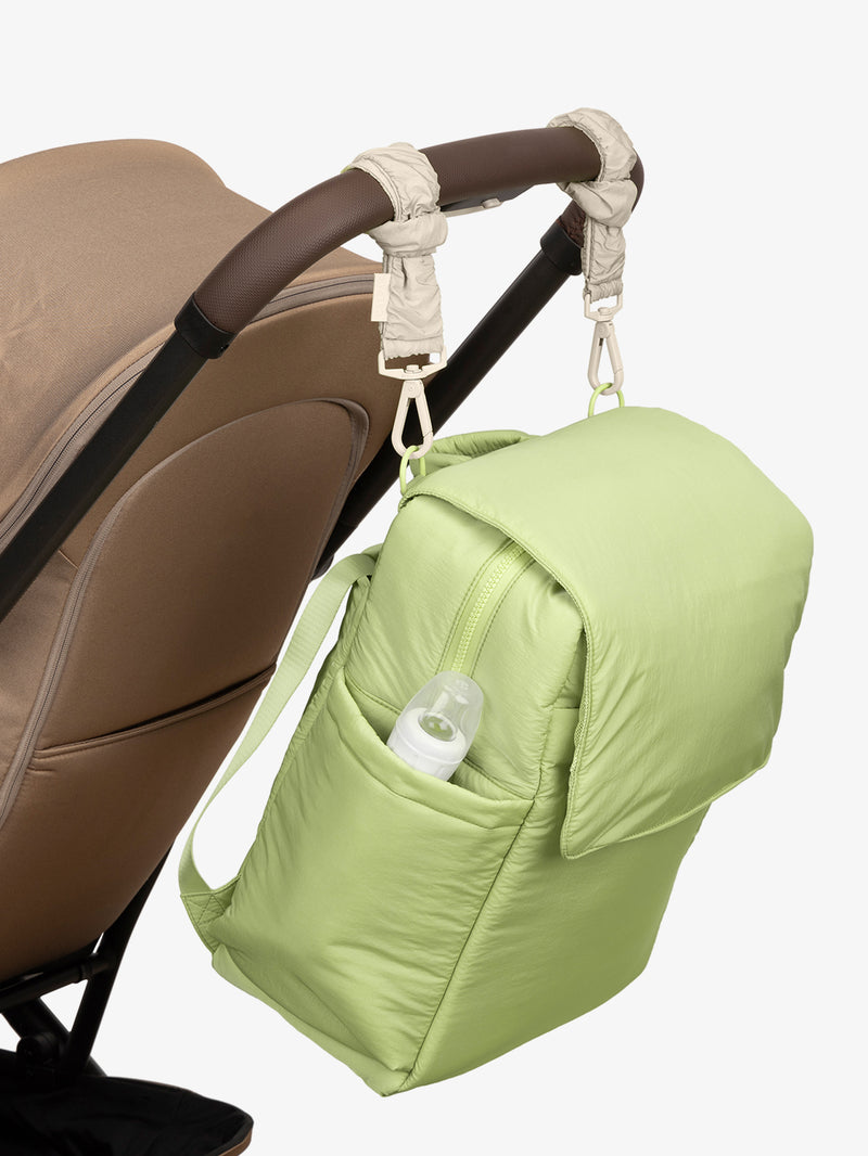 CALPAK Diaper Backpack in light green Lime with white Oatmeal Stroller Straps attached to a brown stroller