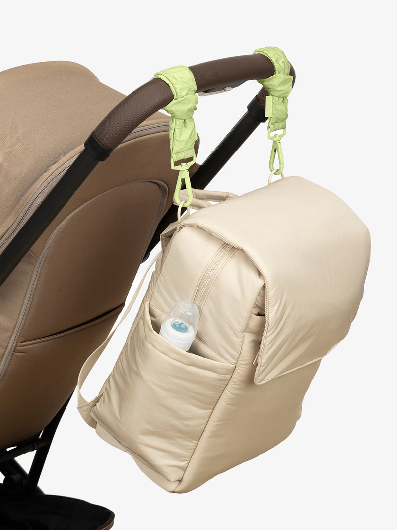 CALPAK Diaper Backpack in white Oatmeal with light green Lime Stroller Straps attached to a brown stroller