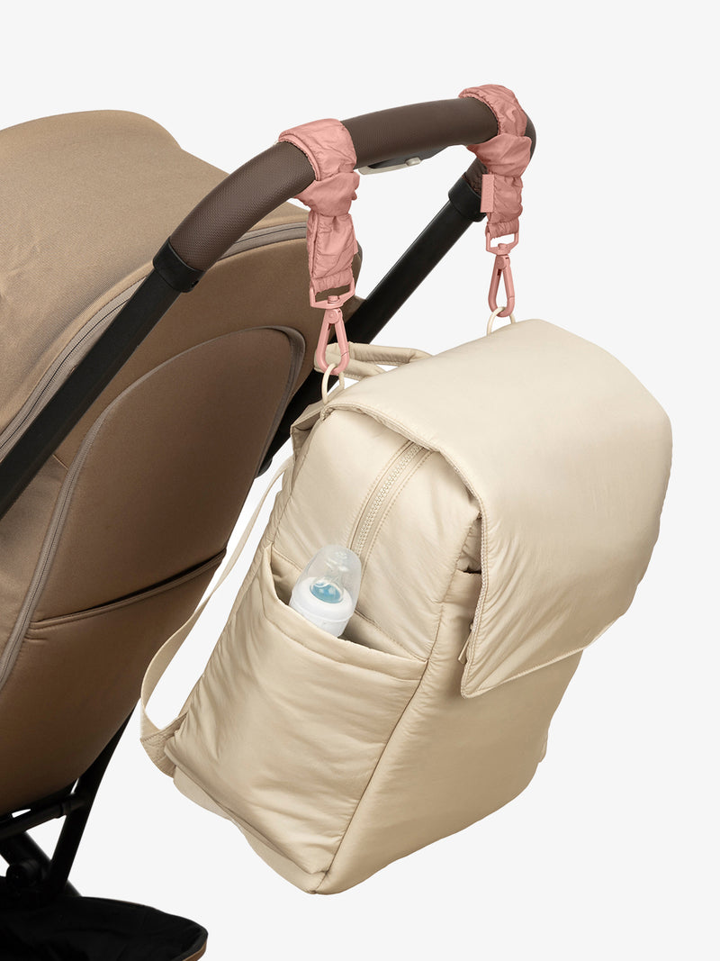 CALPAK Diaper Backpack in white Oatmeal with pink Peony Stroller Straps attached to a brown stroller