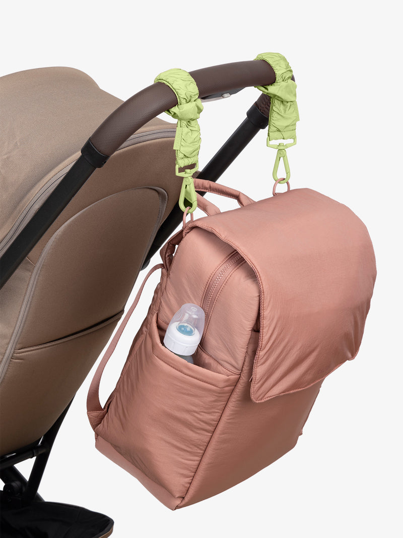 CALPAK Diaper Backpack in pink Peony with light green Lime Stroller Straps attached to a brown stroller