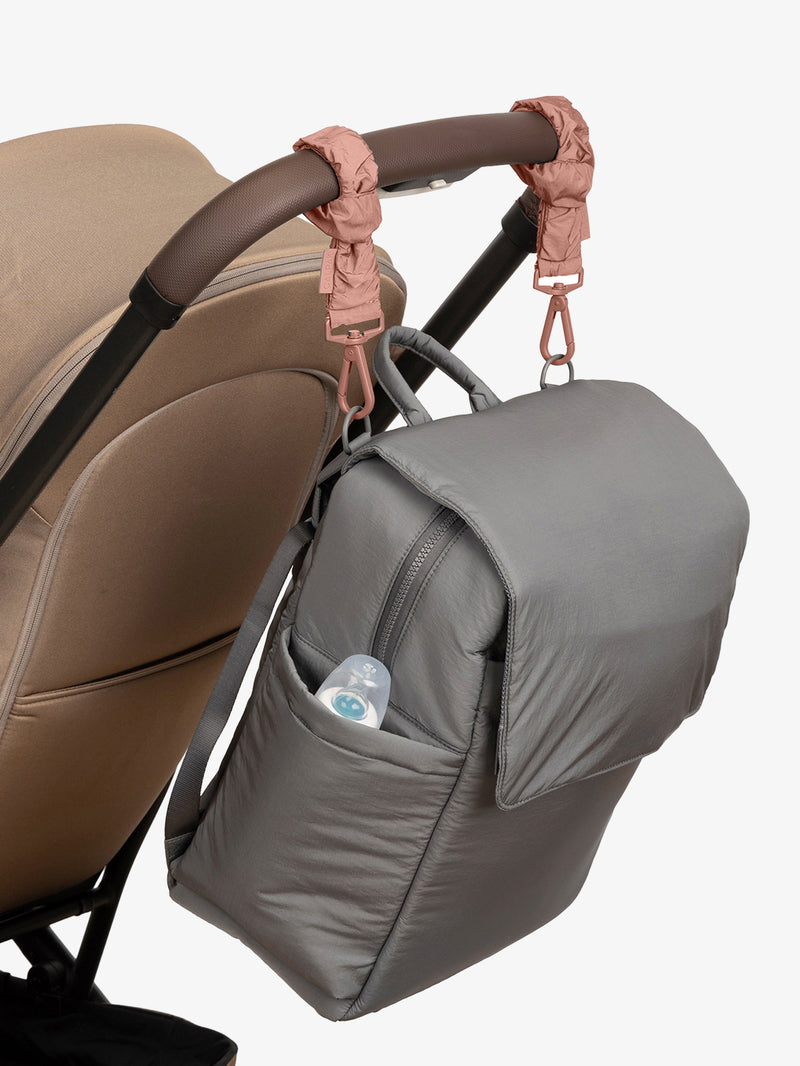 CALPAK Diaper Backpack in grey Slate with pink Peony Stroller Straps attached to a brown stroller