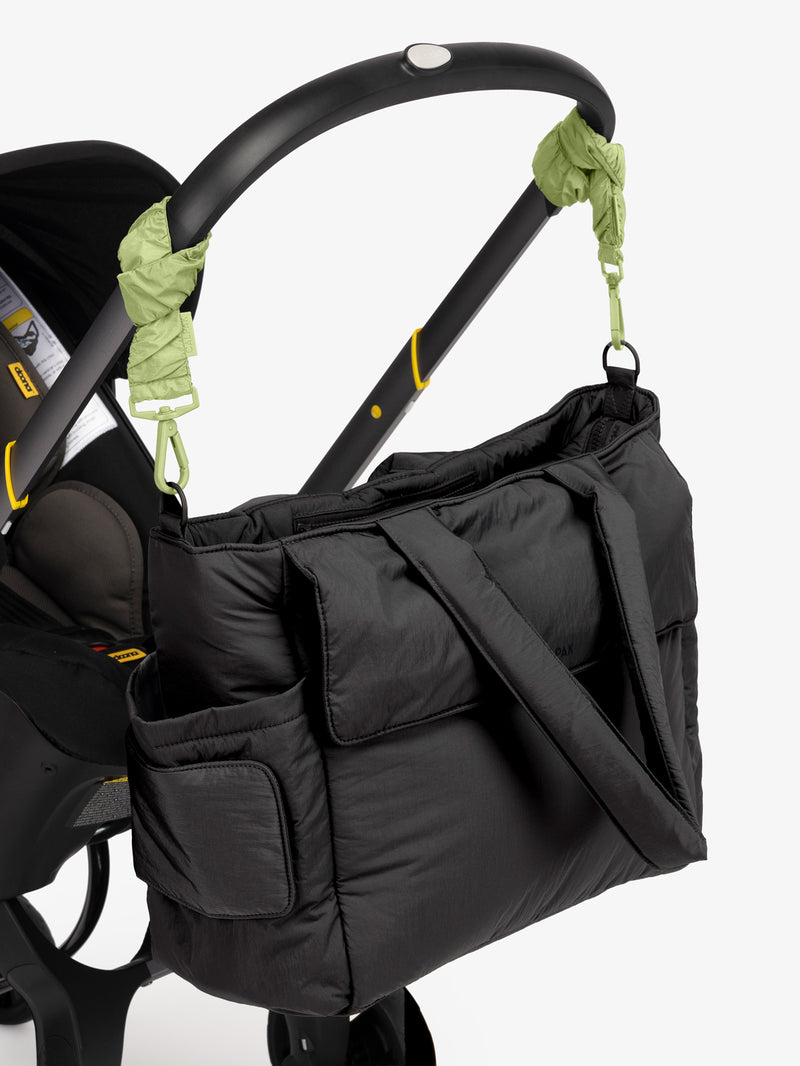 CALPAK Diaper Tote Bag in Black with light green Lime Stroller Straps attached to a black stroller