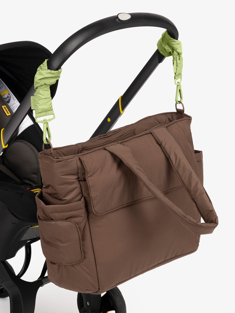 CALPAK Diaper Tote Bag in brown Hazelnut with light green Lime Stroller Straps attached to a black stroller