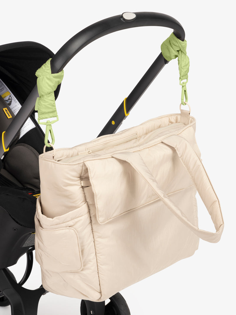 CALPAK Diaper Tote Bag in white Oatmeal with light green Lime Stroller Straps attached to a black stroller