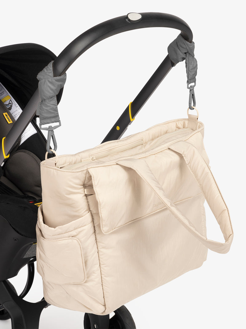 CALPAK Diaper Tote Bag in white Oatmeal with grey Slate Stroller Straps attached to a black stroller