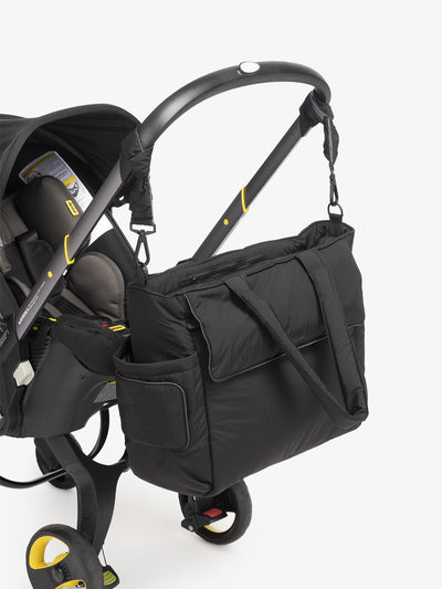 CALPAK Diaper Tote Bag with Stroller Straps attached to stroller handle in black