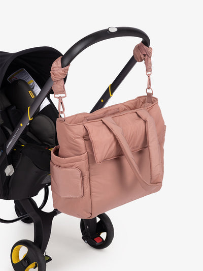 CALPAK Diaper Tote Bag with Stroller Straps attached to stroller handle in peony pink