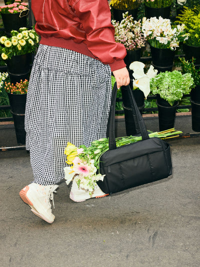 CALPAK Mini Duffel in black front view with puffy exterior, interior and exterior pockets, and padded shoulder straps; DLM2501-MATTE-BLACK view 2