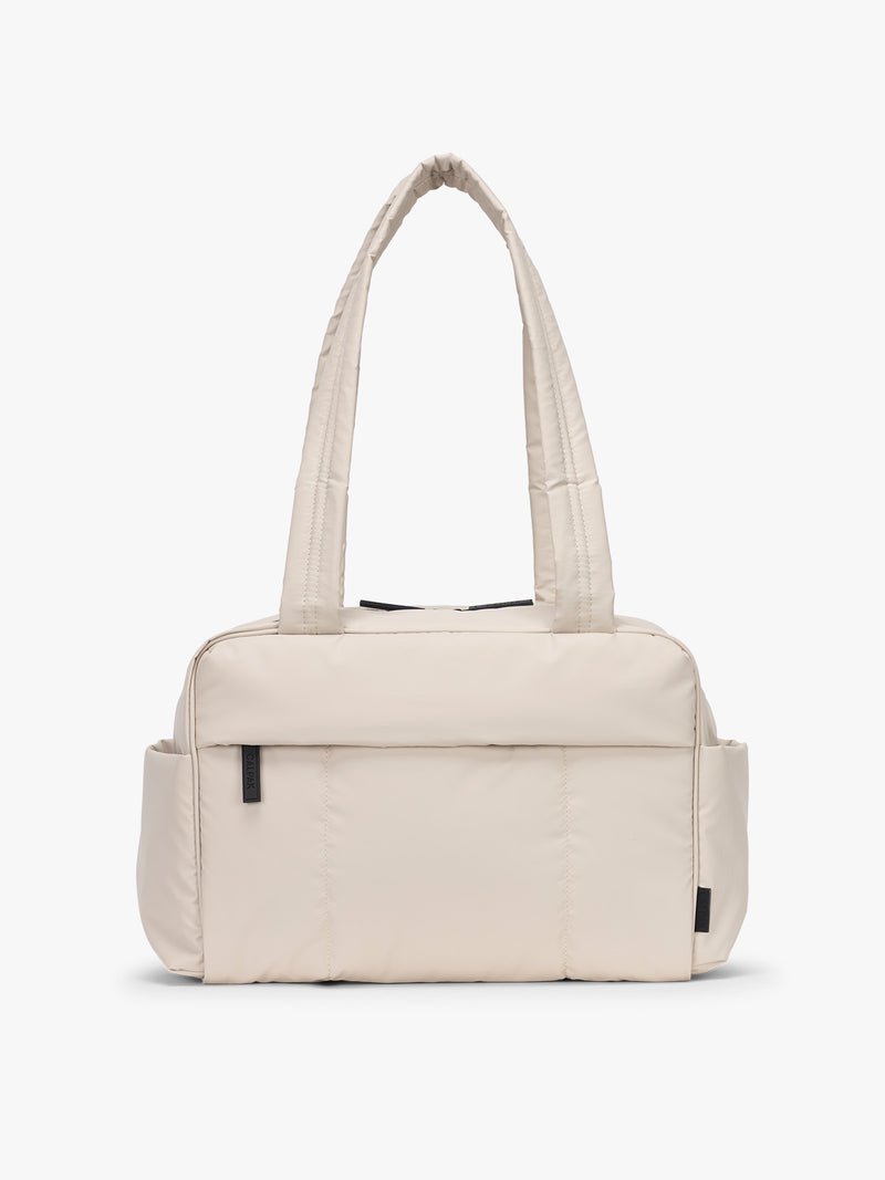 CALPAK Mini Duffel in white Oatmeal front view with puffy exterior, interior and exterior pockets, and padded shoulder straps