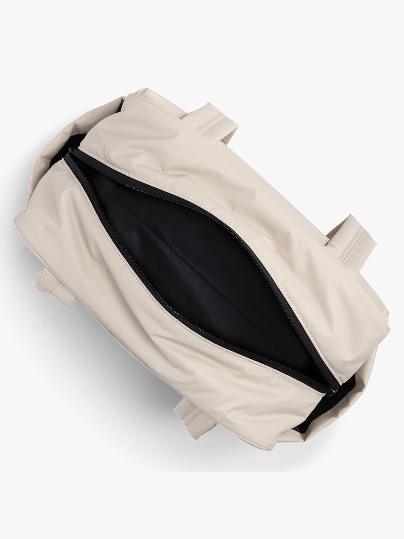 CALPAK Mini Duffel in white Oatmeal open interior with puffy exterior, interior and exterior pockets, and padded shoulder straps