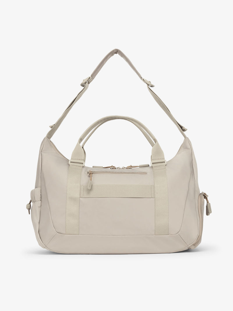 Back view of CALPAK Fit gym sling duffel bag with zippered phone pocket in beige