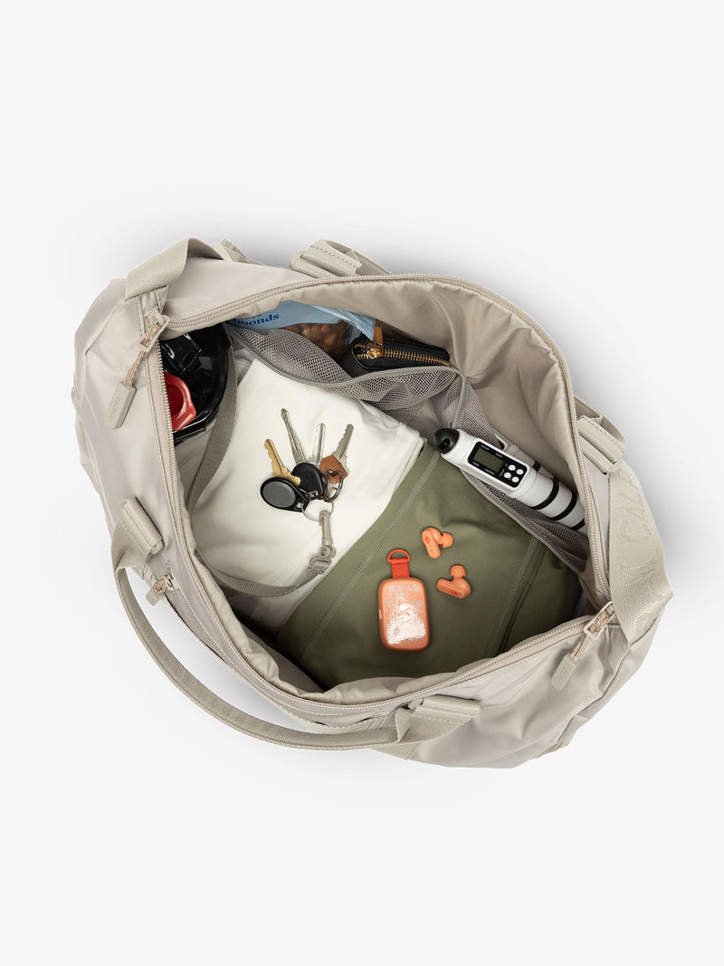 Interior view of grayish beige CALPAK Fit Gym Bag with personal belongings packed within