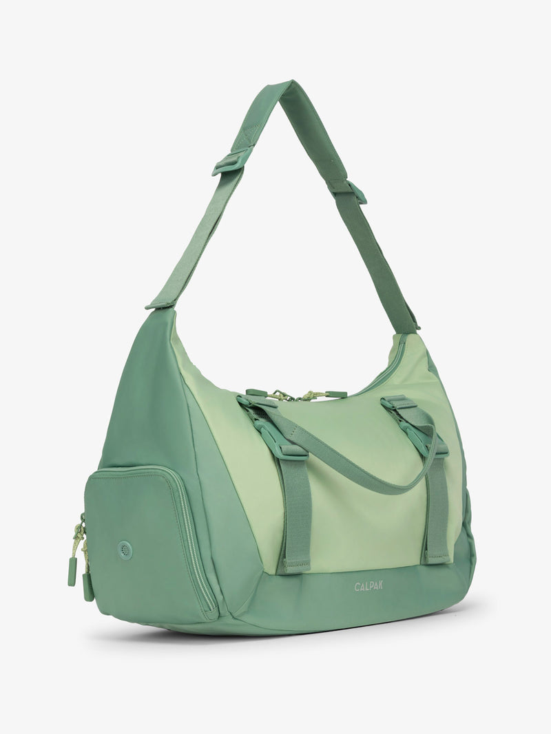 Side view of CALPAK Fit gym duffel bag with shoe compartment and adjustable yoga mat straps in sage green