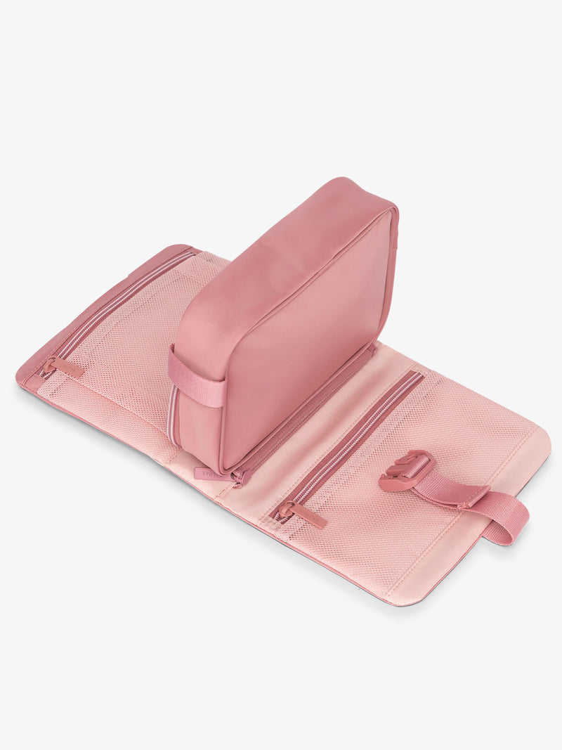 Flat lay of CALPAK Fit gym dopp kit with multiple interior mesh pockets in tea rose