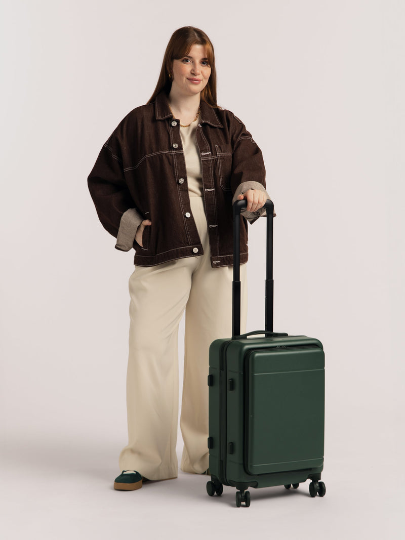 Model with CALPAK Hue Front Pocket Carry-On Luggage with telescopic handle in green Emerald