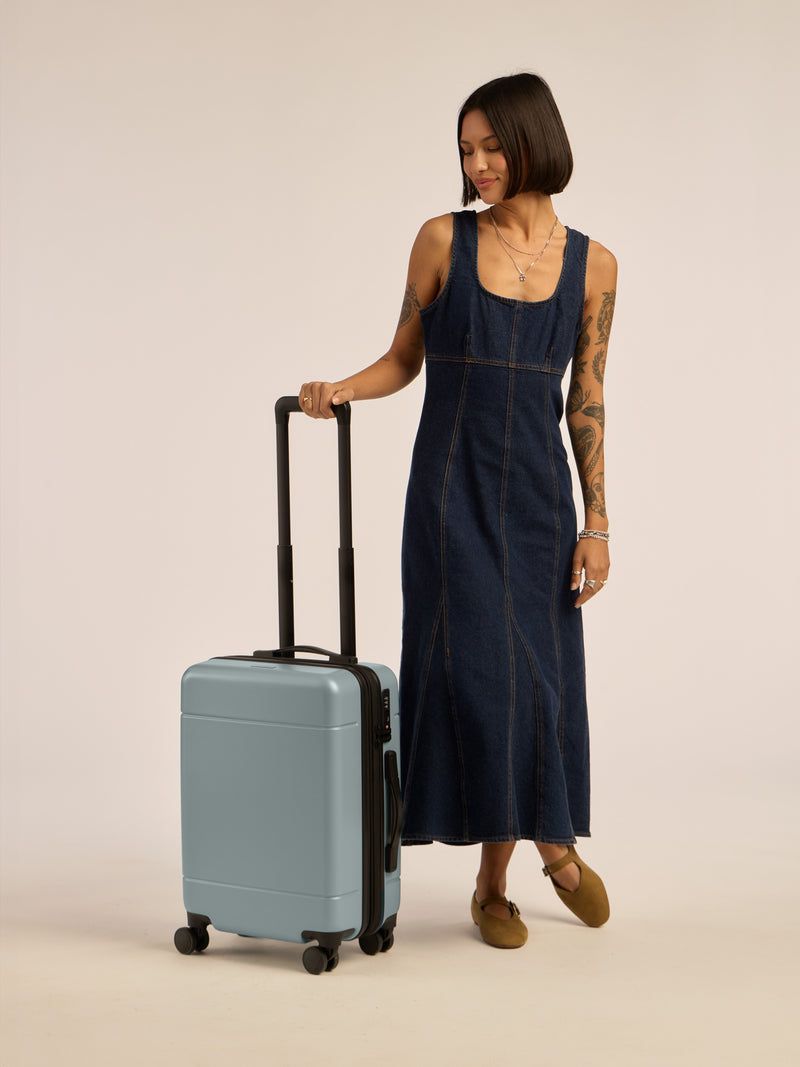 Model with CALPAK Hue Carry-On Luggage in blue Bluebell