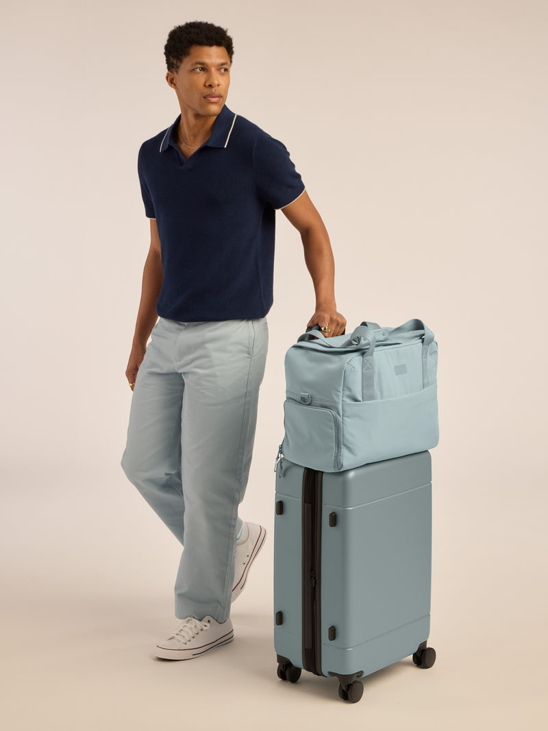 Model with CALPAK Hue Medium Luggage in blue Bluebell