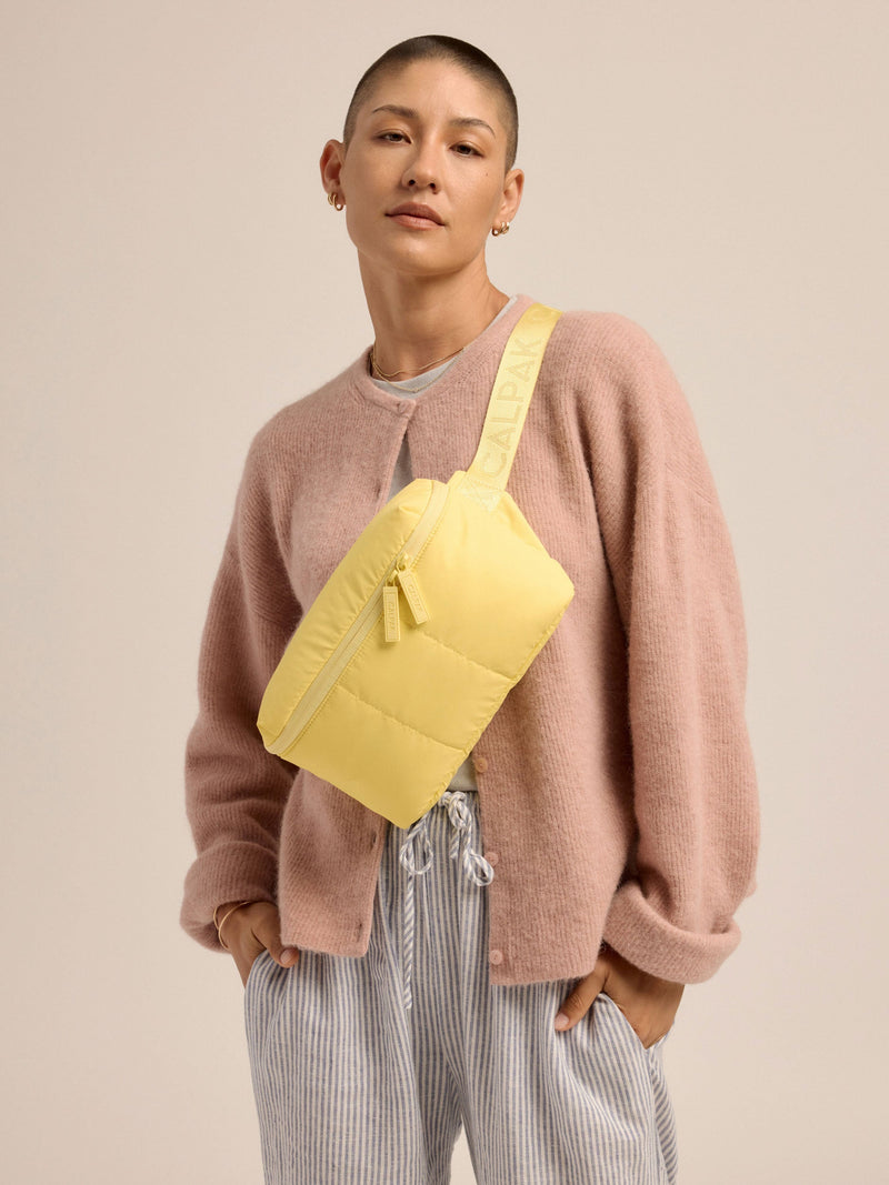 Model wearing yellow CALPAK Luka Belt Bag as crossbody bag