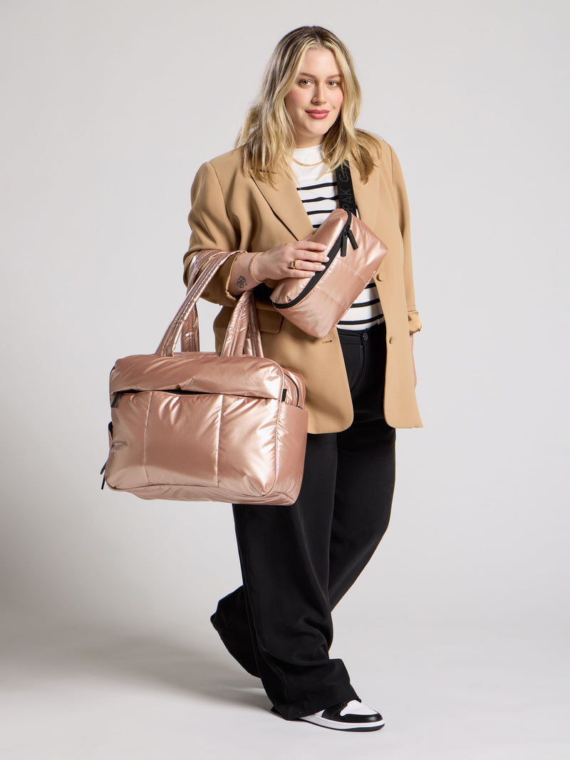 CALPAK Model wearings metallic rose gold belt bag as crossbody bag and luka duffel bag over shoulder