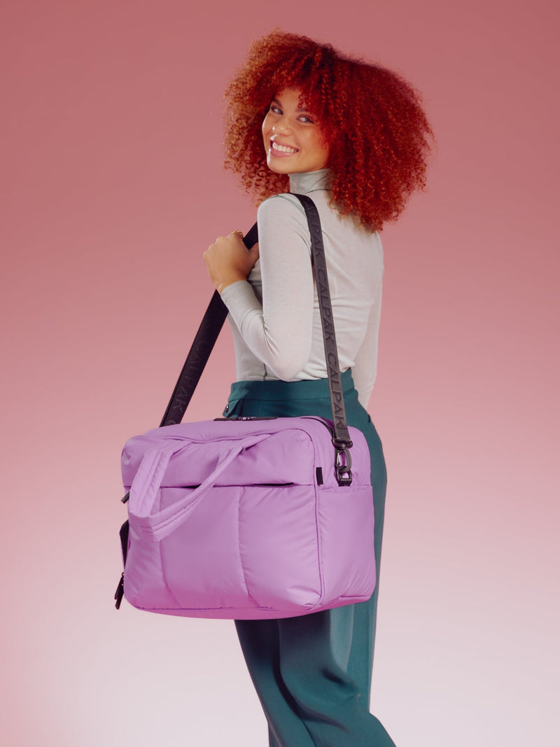 Model wearing CALPAK Luka Duffel in lavender over shoulder with detachable shoulder strap