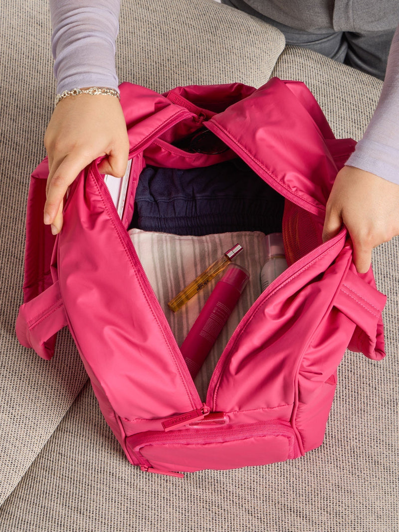 Model showing the monochrome dragonfruit pink interior of CALPAK luka duffel