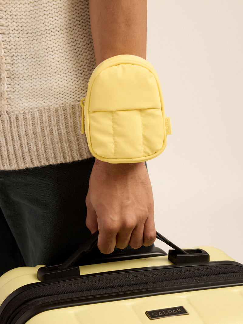 Model wearing CALPAK Luka Key Pouch on wrist in butter yellow