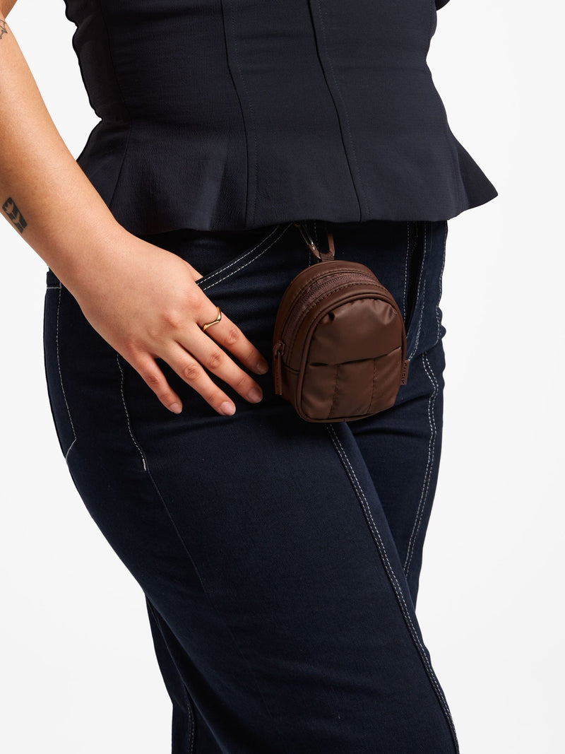 Model wearing walnut CALPAK Luka Key Pouch attached to belt loop by carabiner clip