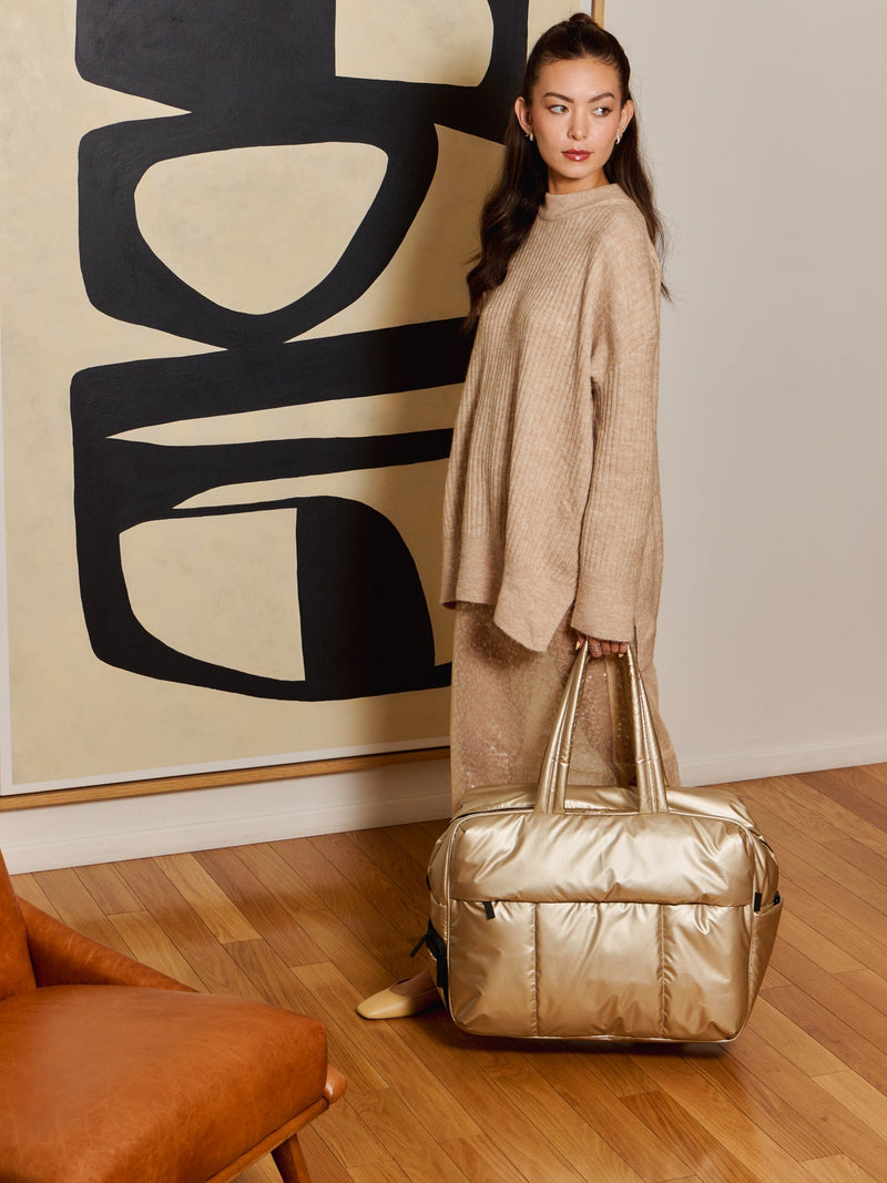 Model holding metallic gold Luka Large Duffel