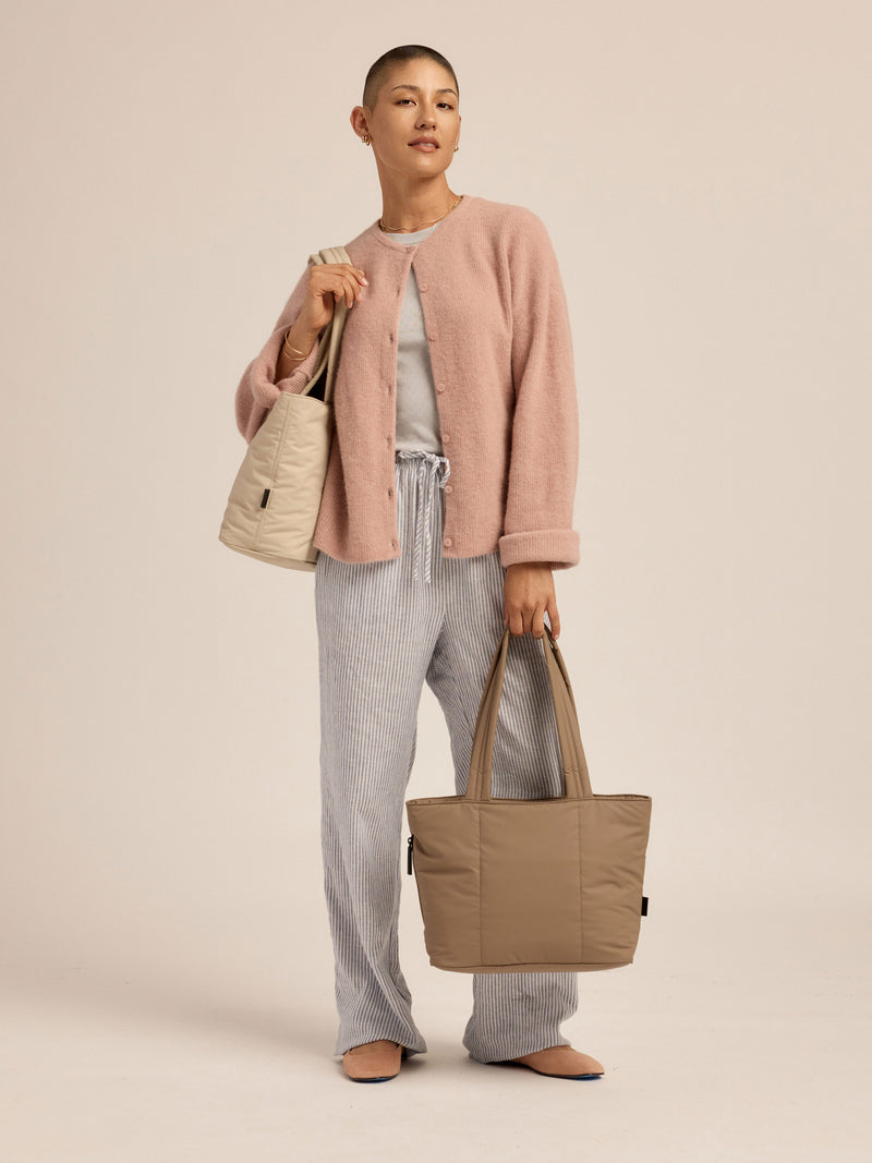 Model wearing oatmeal CALPAK Luka Mini Tote over shoulder with the chocolate Luka Mini Tote in the other hand