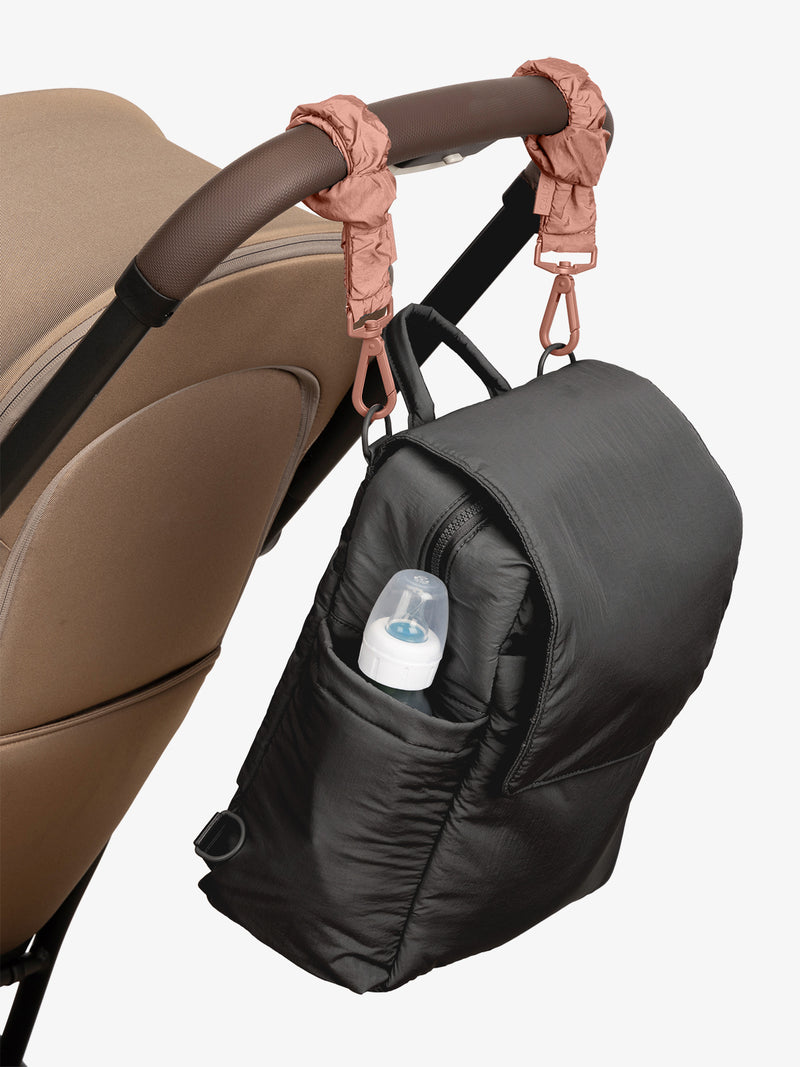 CALPAK Convertible Mini Diaper Backpack in Black with pink Peony Stroller Straps attached to a brown stroller