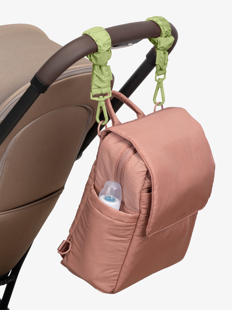 CALPAK Convertible Mini Diaper Backpack in pink Peony with light green Lime Stroller Straps attached to a brown stroller