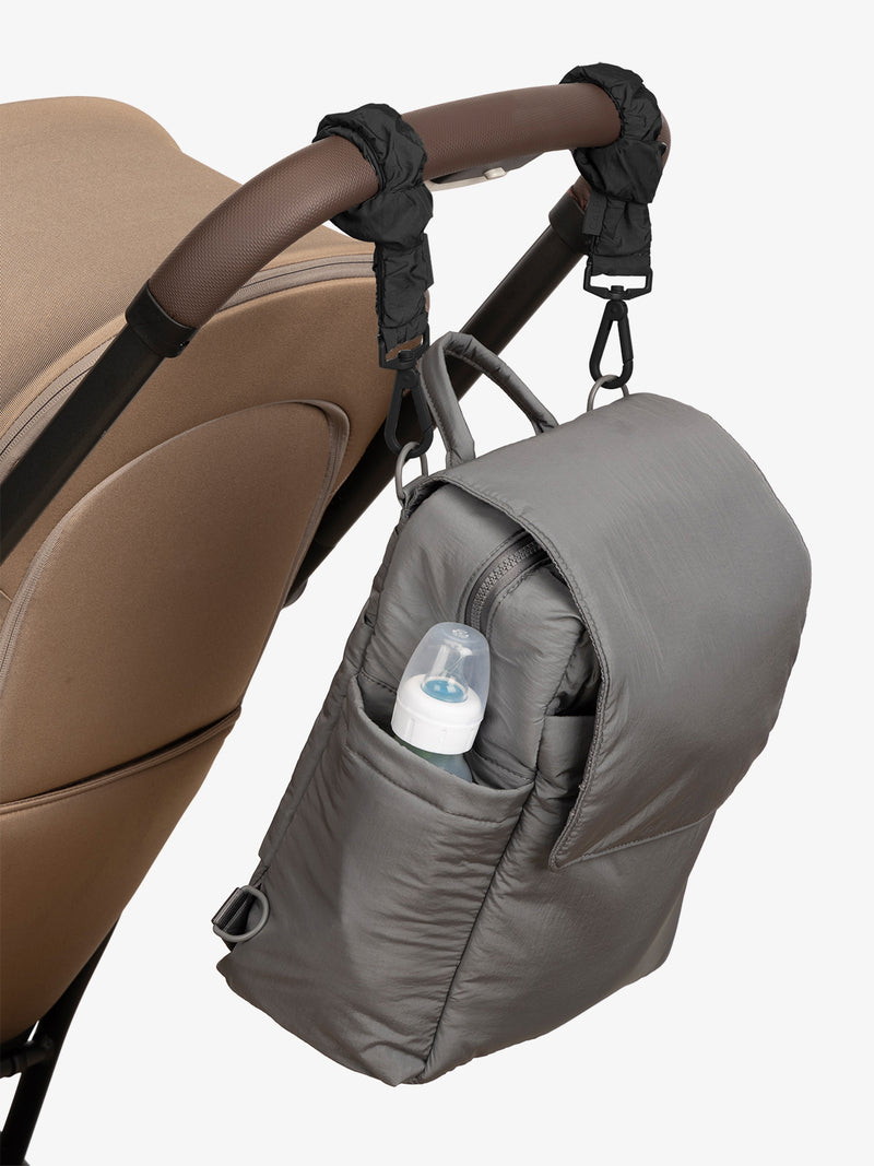 CALPAK Convertible Mini Diaper Backpack in grey Slate with Black Stroller Straps attached to a brown stroller