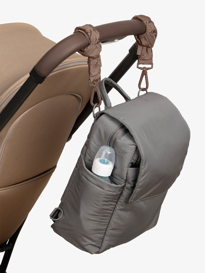 CALPAK Convertible Mini Diaper Backpack in grey Slate with brown Hazelnut Stroller Straps attached to a brown stroller