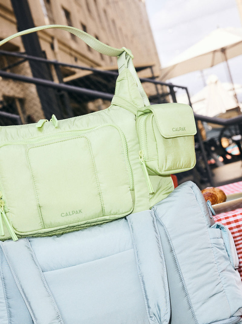 CALPAK Baby Collection Pacifier Pouch in light green Lime clipped onto CALPAK light green Lime Crossbody Diaper Bag