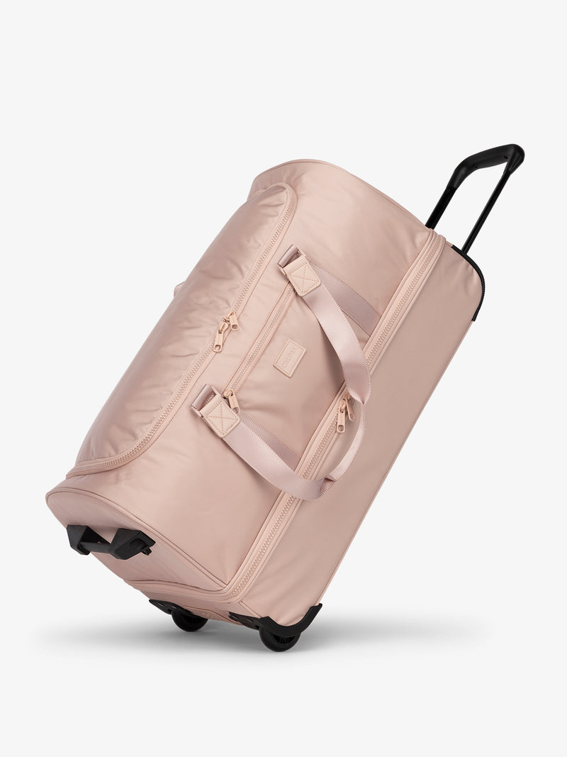 Side view of CALPAK Stevyn Large Rolling Duffel in pink sand